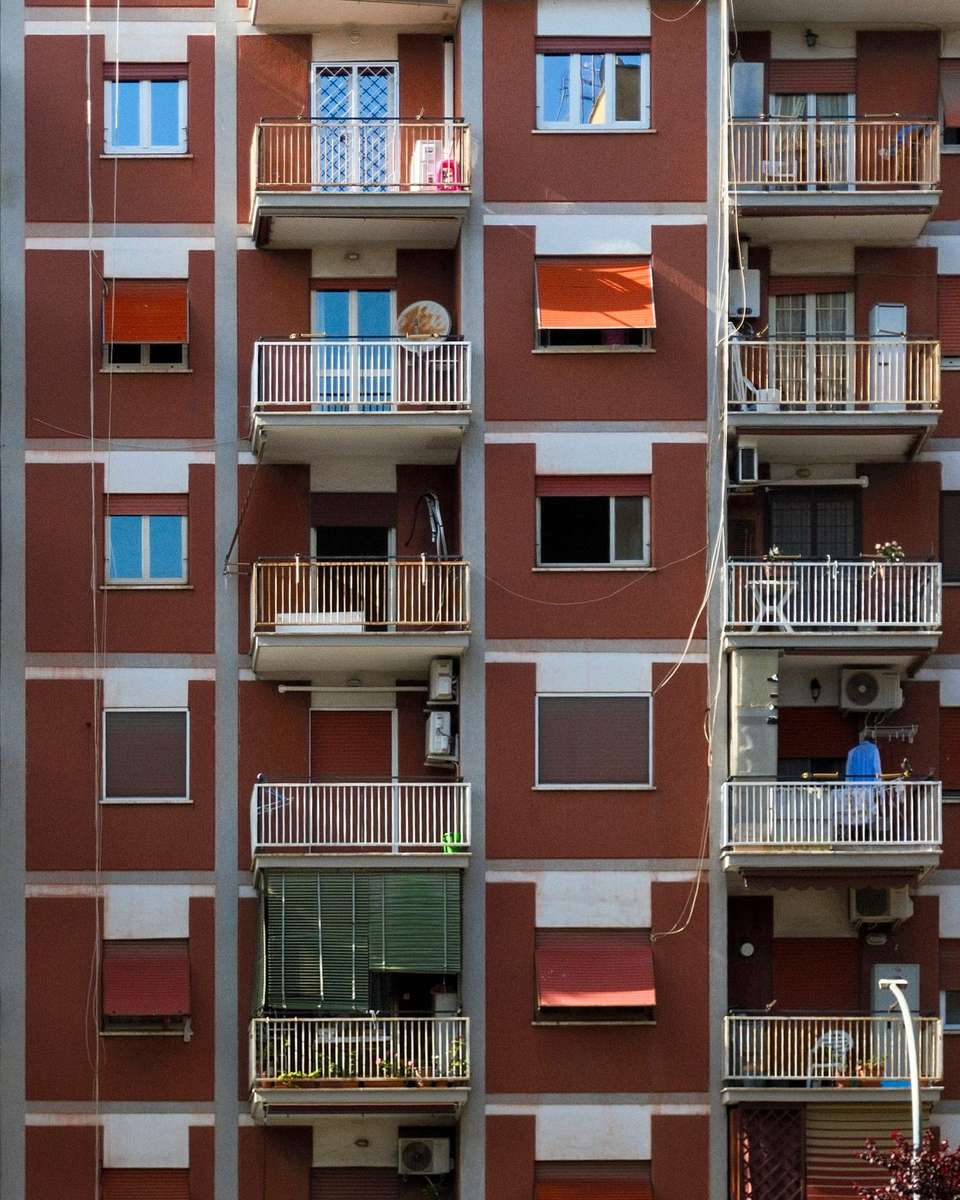 Fachada de un bloque de pisos de ladrillo con balcones y toldos