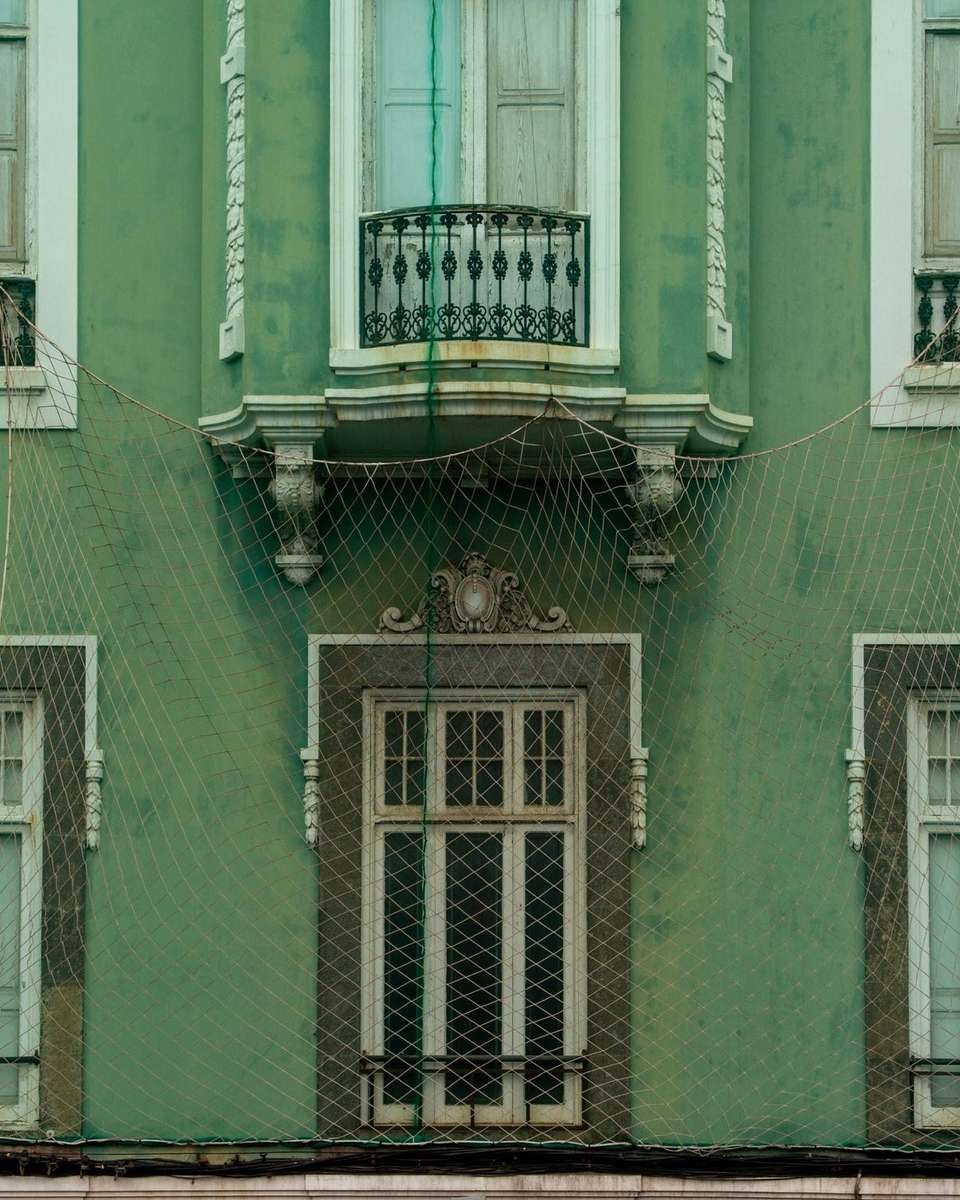 Fachada verde con balcones acristalados y ventanas blancas en Las Palmas de Gran Canaria
