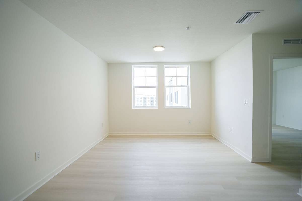Habitación vacía de paredes blancas, suelo de madera y una ventana al fondo